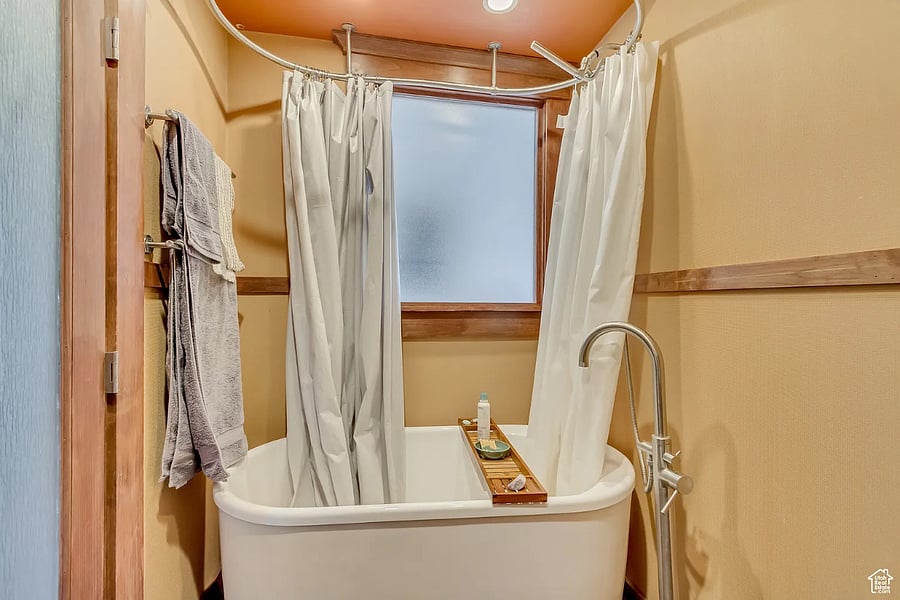 Deep soaking tub with curved shower rail and frosted window.