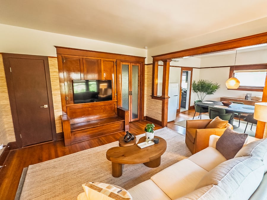 The elevated living room with warm, cherry hardwood details, city and mountain views, plenty of natural light, and lots of seating clustered around organic wood coffee tables.