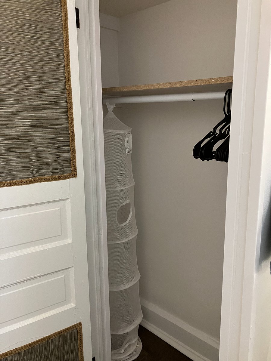 Interior view of the closet with hangers and storage caddy and shelf