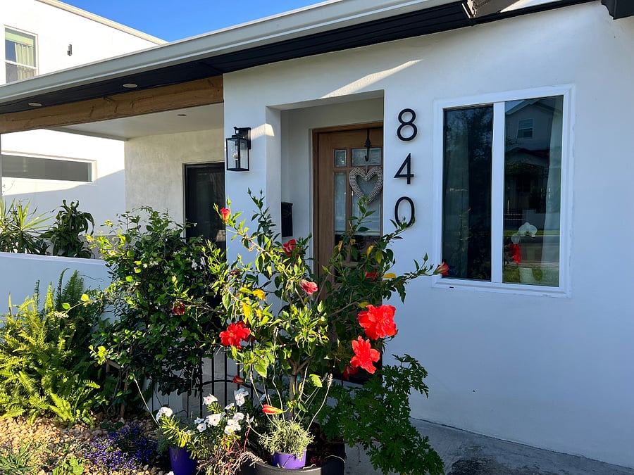 Welcoming front entrance with a custom wood door, fragrant jazmine and a colorful azalea tree. 