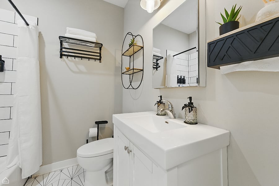 A modern, thoughtfully designed bathroom featuring a sleek vanity, geometric tile floors, and matte black fixtures.