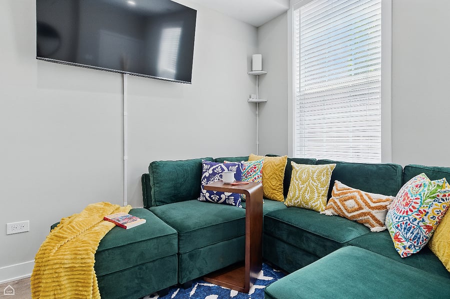 A cozy, colorful living space featuring a smart 55" TV with Netflix, Disney+, and Hulu. The super comfortable sectional invites you to relax instantly, while vibrant natural light livens the room by day and blackout conditions create a movie-theater feel at night.

