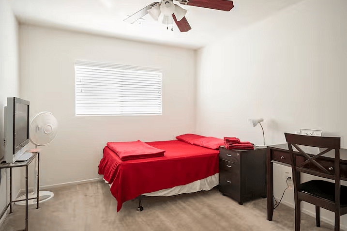 The Ruby Room with queen size bed, workspace, and Smart TV.