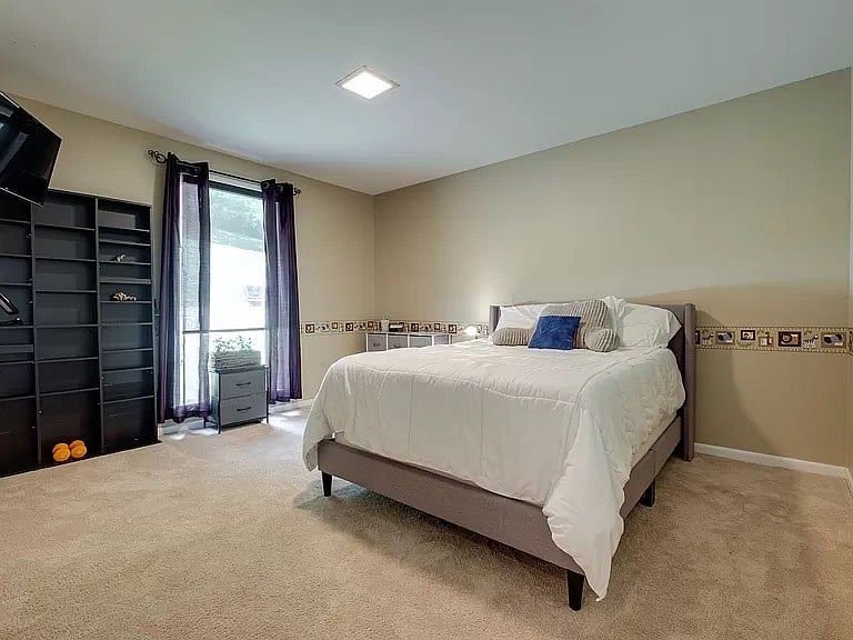 This is full-sized bedroom. Wall decor is still a whimsical chair-rail height border. TV is mounted in the corner to the left.
