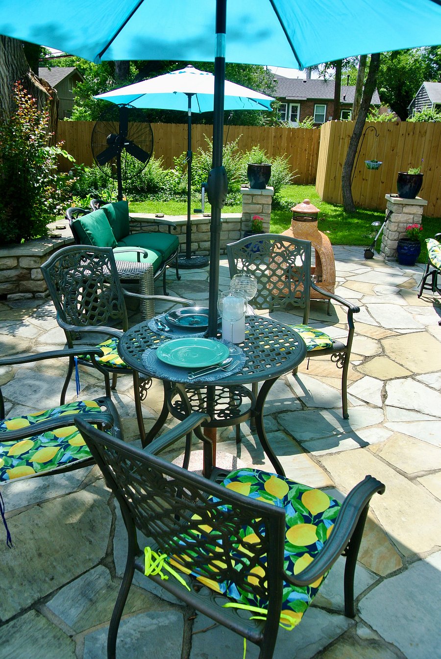 Large stone patio with Chiminia, outdoor furniture and propane grill.