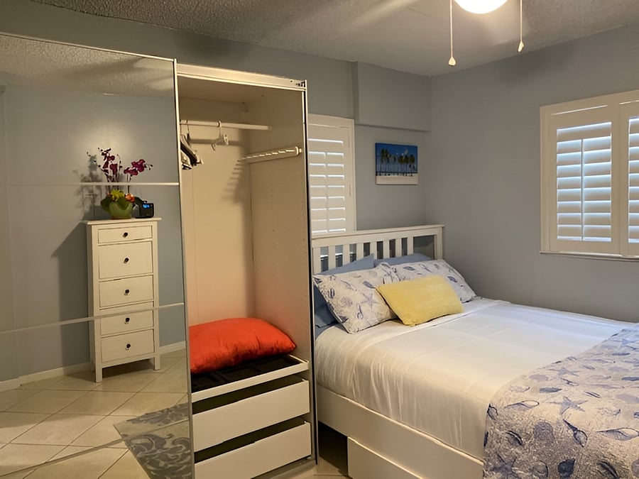 2nd bedroom: Mirrored closet open, extra pillows and blankets within, dresser (reflection in the mirror).