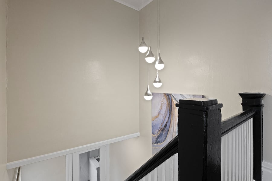 Stairs up to apartment featuring chandelier and art.