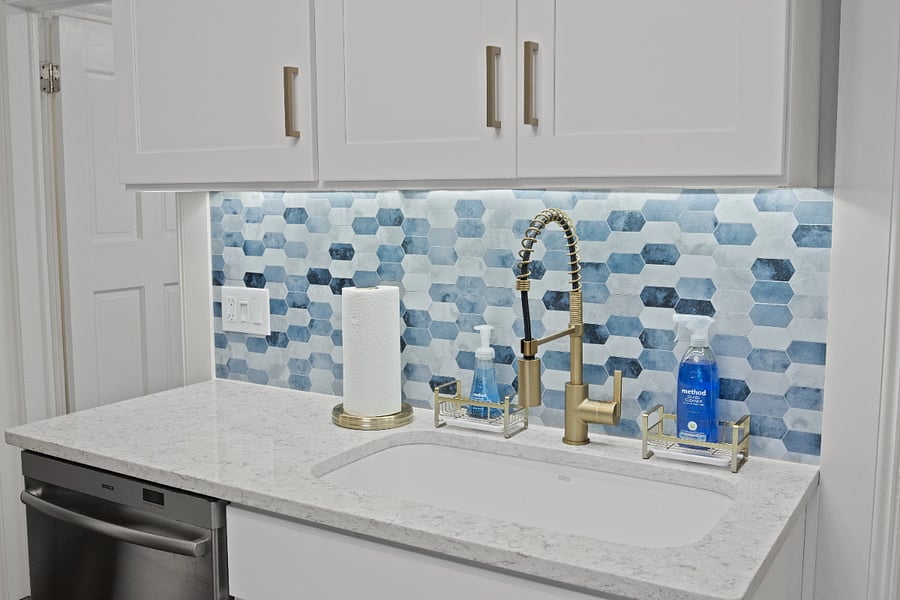 Sink and dishwasher featuring colorful backsplash and cleaning products
