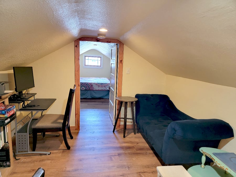 Sitting room with computer desk, couch, and 2 coffee tables just outside the bedroom