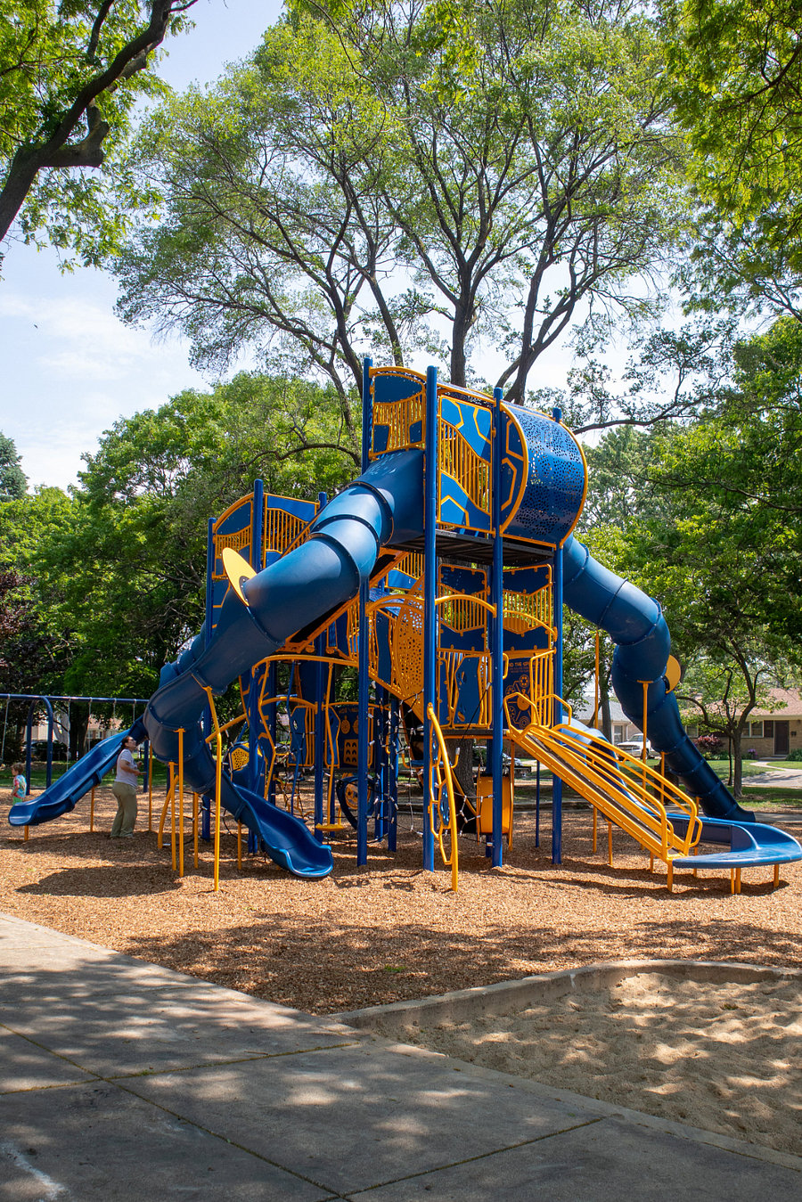 Outdoor recreation one block down the street at park with basketball courts, tennis courts, pickleball court overlay, a baseball field, walking paths, open green areas, a large playground and picnic areas with shelter and tables.