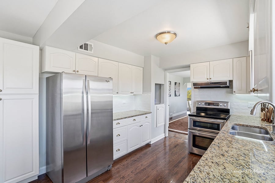 Sun-kissed kitchen with under-cabinet lighting highlighting the warm and timeless Tuscan granite counter-tops and all stainless steel appliances.