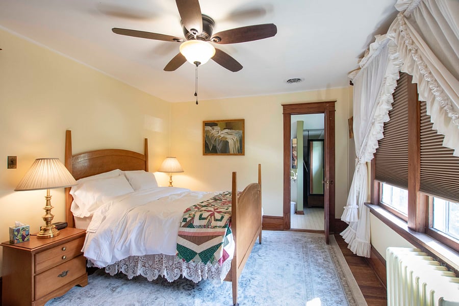 This upstairs bedroom has a double bed, dresser and clothing armoire. It has a connecting door to the upstairs bath