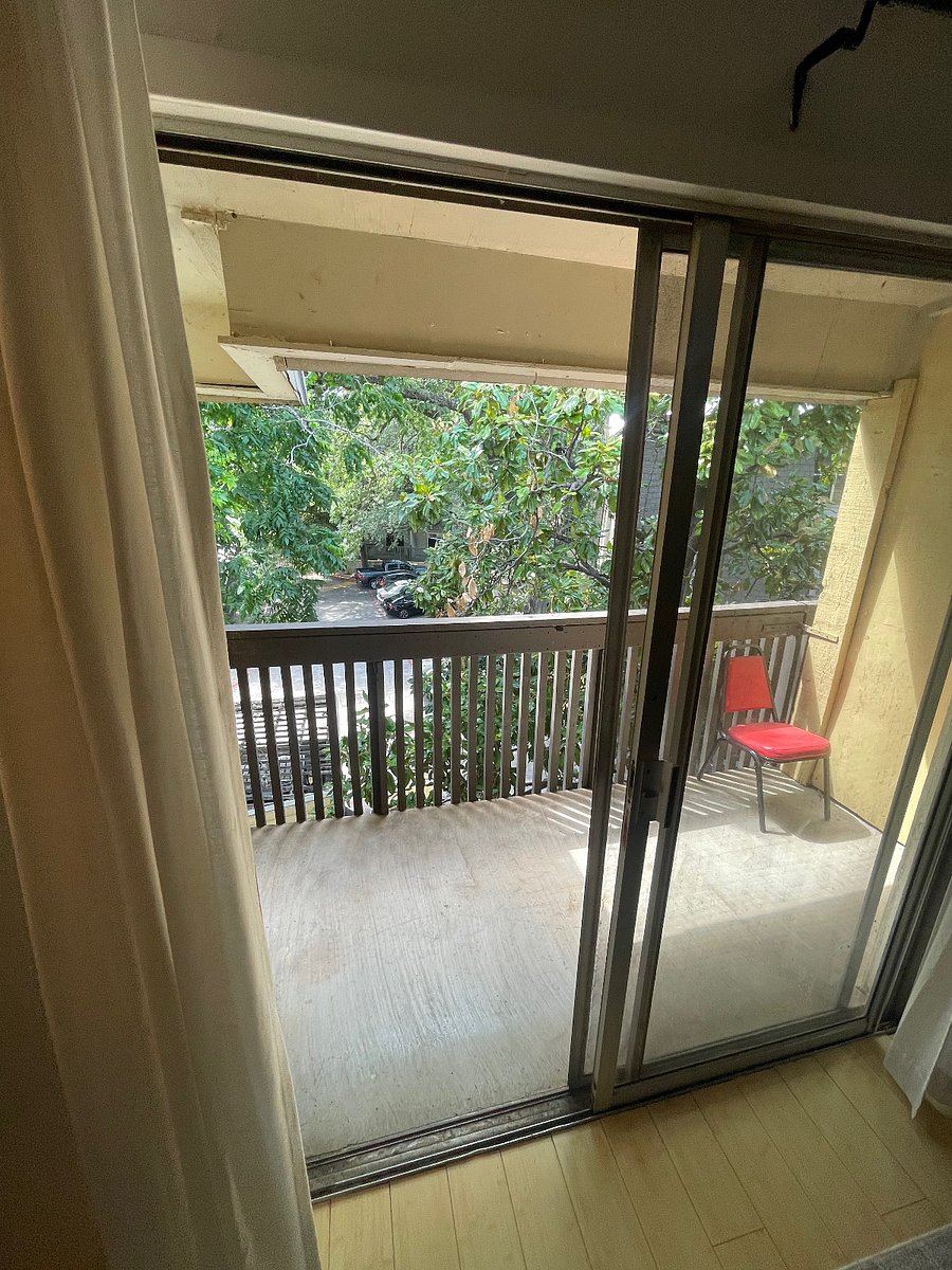 Patio with screen door. View of parking lot, magnolia trees and oak trees.