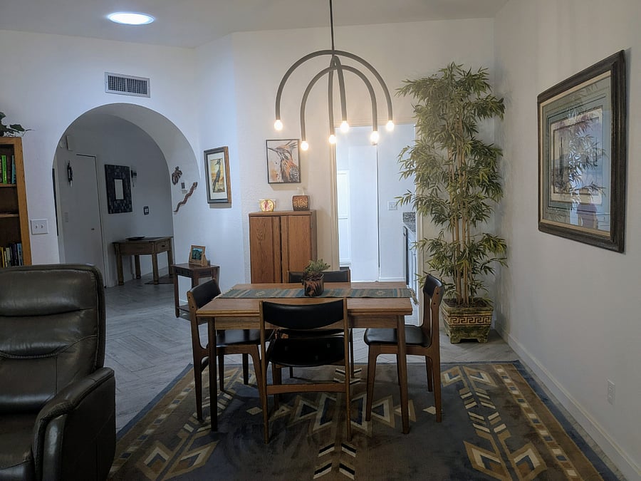 View of dining area and chandelier with arches to kitchen and front hallway.