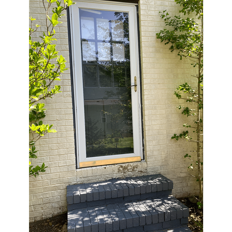 Secure private entrance with storm door and deadbolt lock for safety.