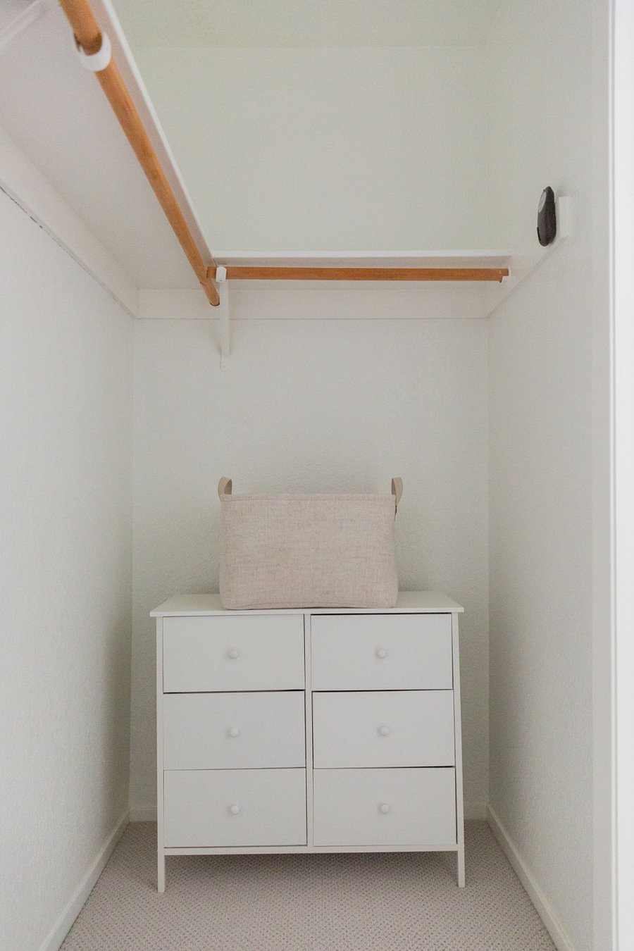 Walk in closet with small dresser and clothes basket.