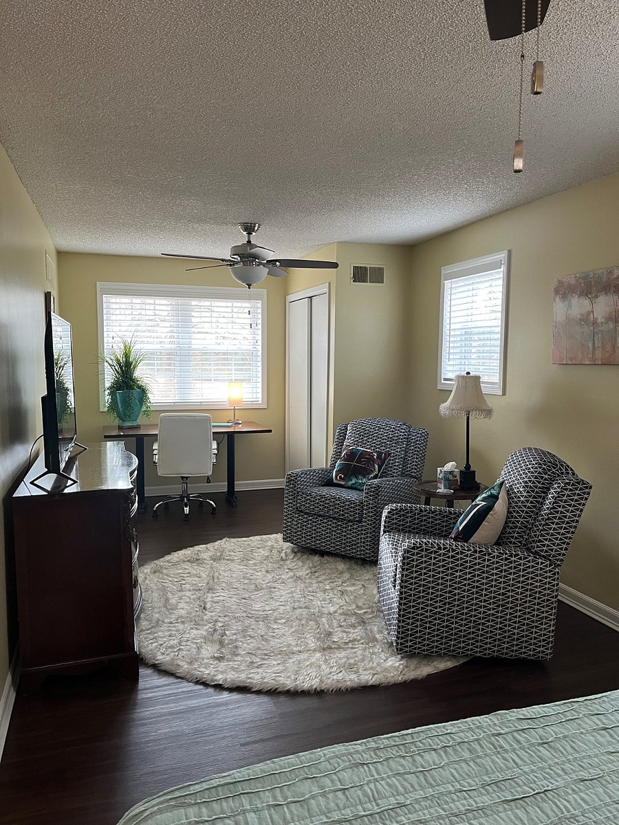 Master bedroom with two rockers and smart TV with table for office work.