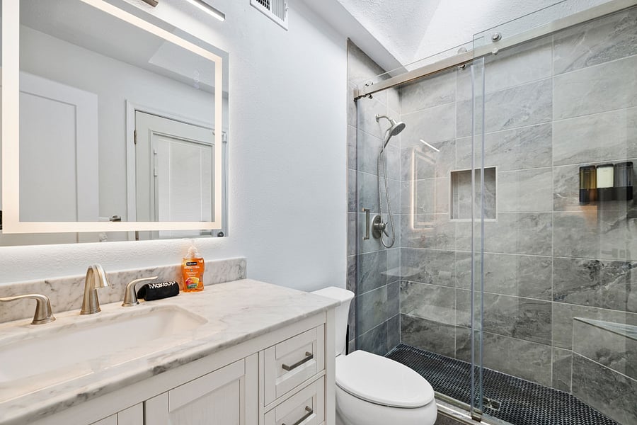The en-suite bath features a marble-topped vanity, LED-lit mirror, and a sleek walk-in showermodern comfort with spa-like touches.