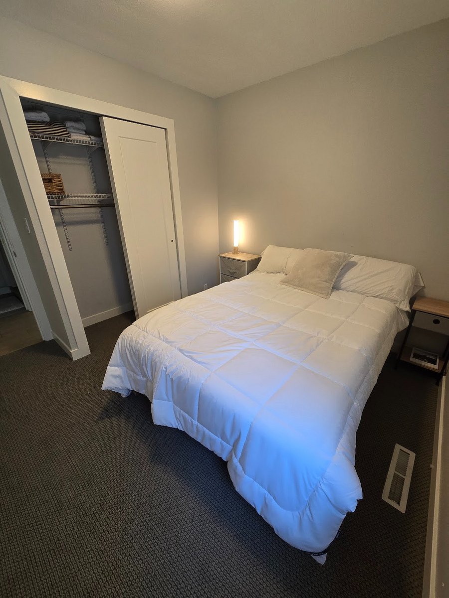 Middle bedroom with a full/double bed. Across the hallway is a bathroom with toilet, sink, and shower.