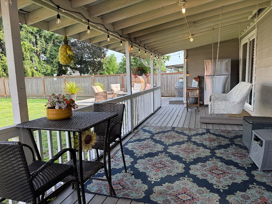 Spacious covered patio with seating, BBQ, patio swing, and outdoor fridge.