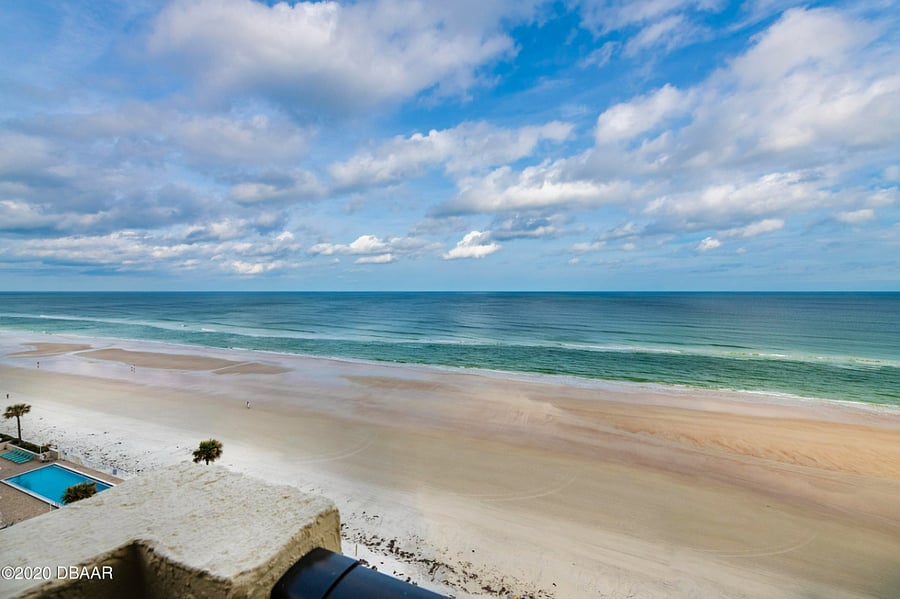 The view of the beach from the 11th floor balcony. The balcony has two adirondack chairs.