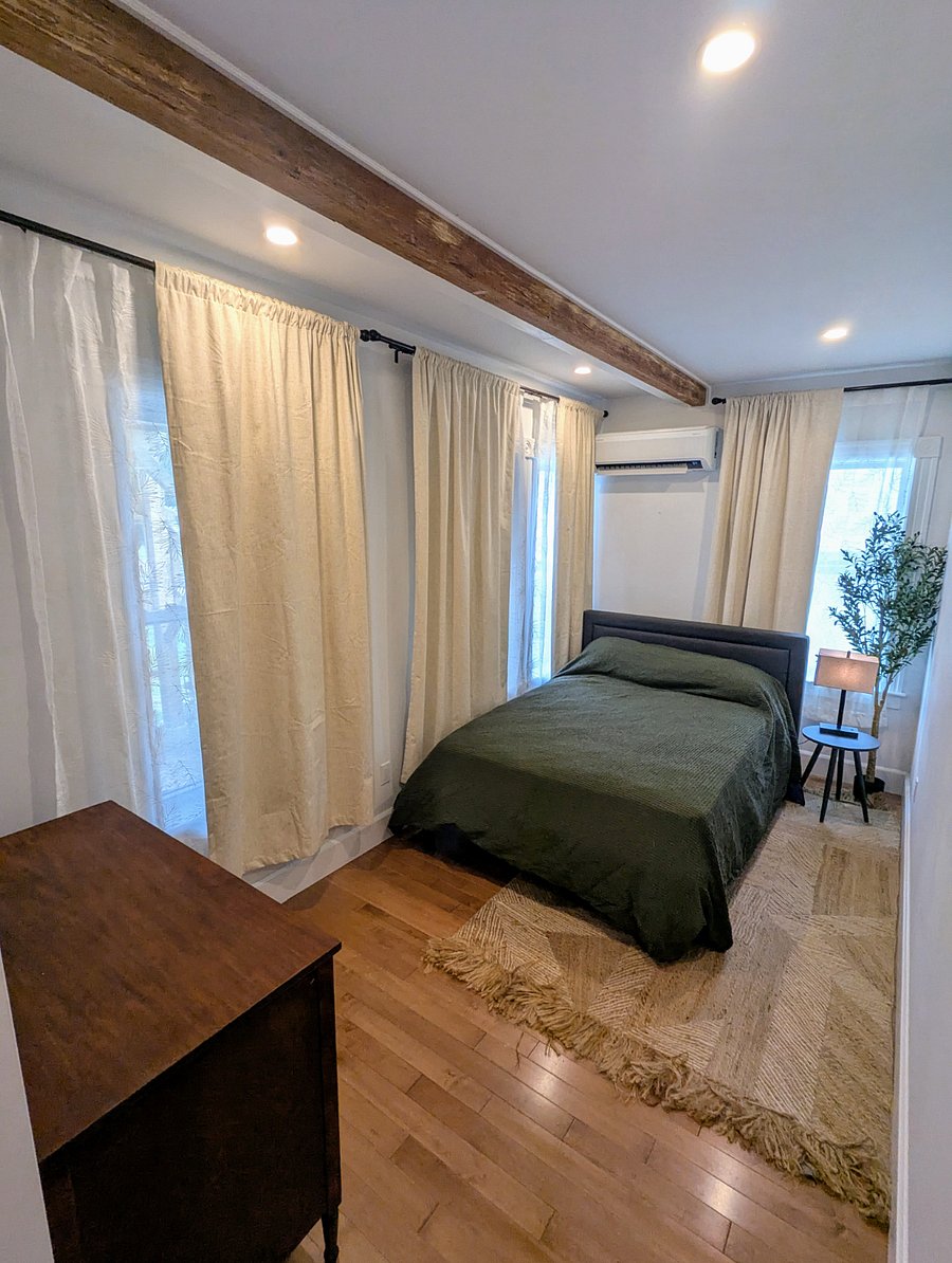Bedroom #3 with full bed, dresser, small closet, and personal heat/ac unit. Light blocking curtains.