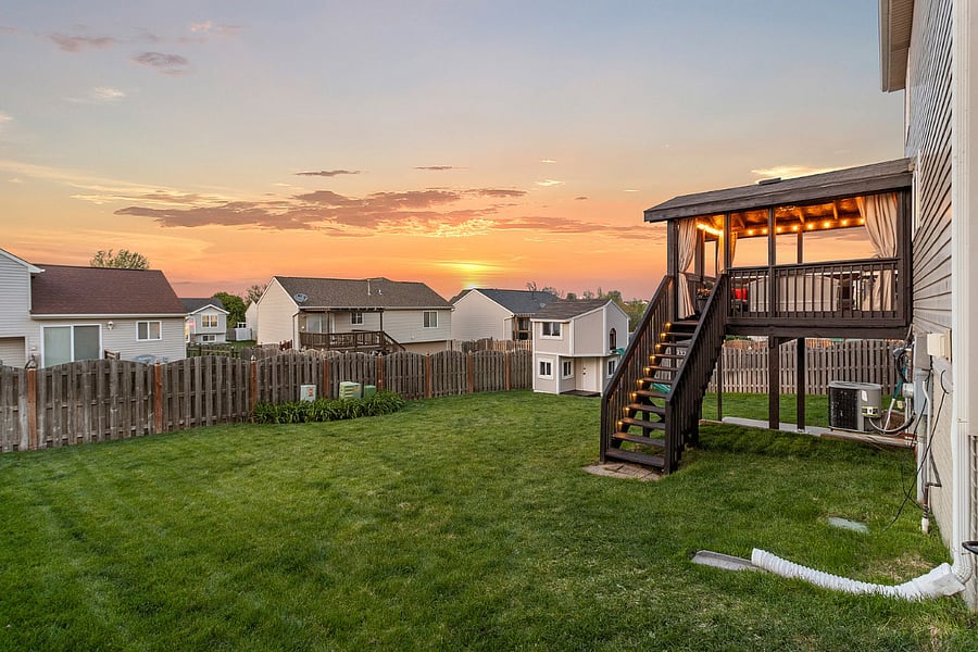 Fenced backyard with deck and playhouse.