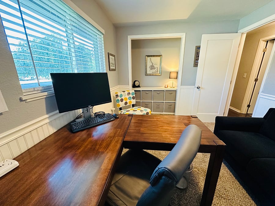 Office with L-shaped desk, office chair, monitor, keyboard, shelving, and printer