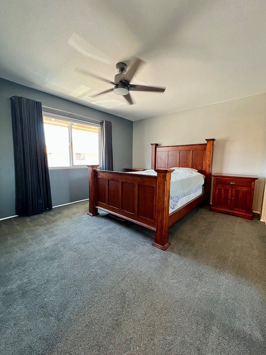 Primary bedroom with floor-length blackout curtains and end tables on both sides of the bed.