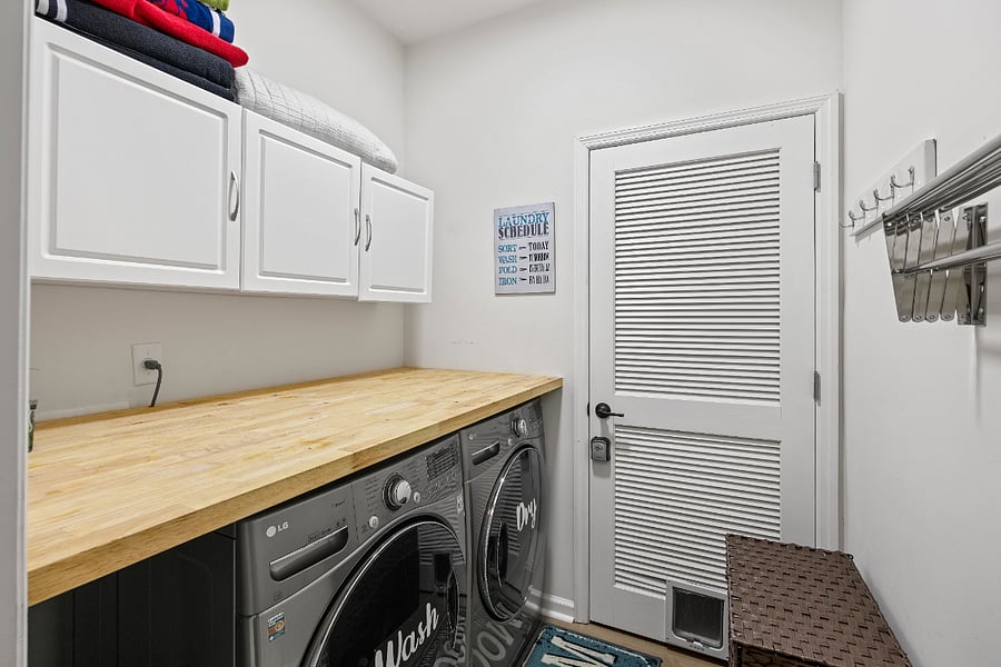 A shared laundry room with a modern washer and dryer, available for your convenience. Equipped with ample counter space and storage for easy use.