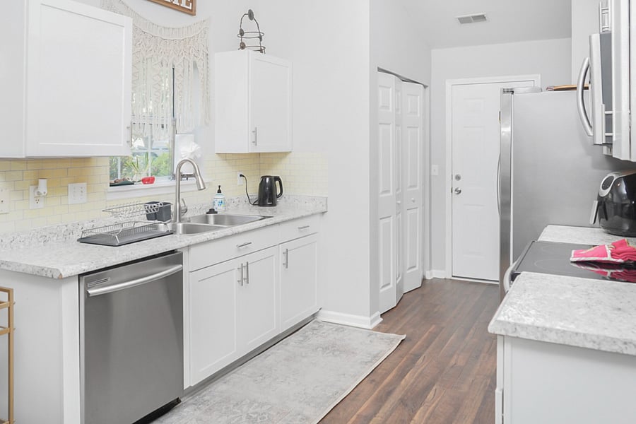 This bright kitchen boasts a double sink, dishwasher, and plenty of cabinet space for all your cooking essentials. A large window fills the space with natural light, creating a cheerful spot to prep and cook your favorite meals.