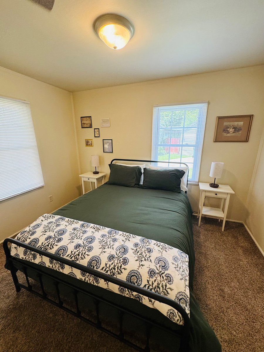 Queen size bed and workspace in a spacious room. Several windows for natural light