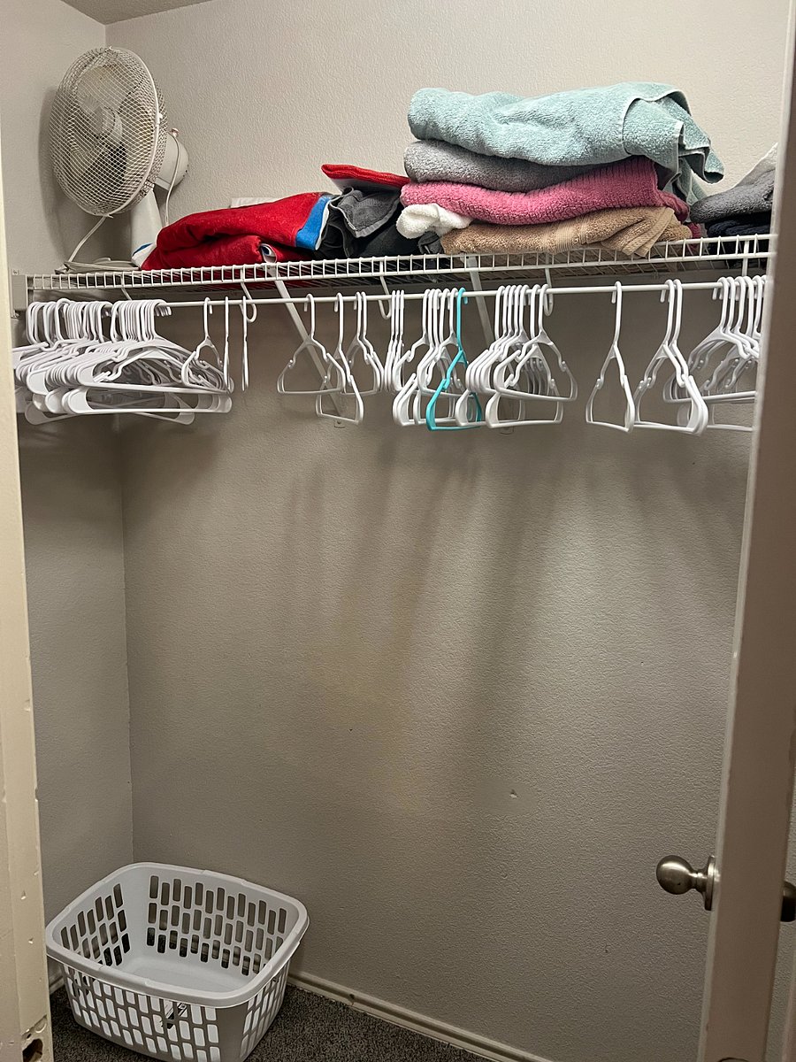 Closet space with plenty of hangers, laundry basket, towels, pool towels and a fan