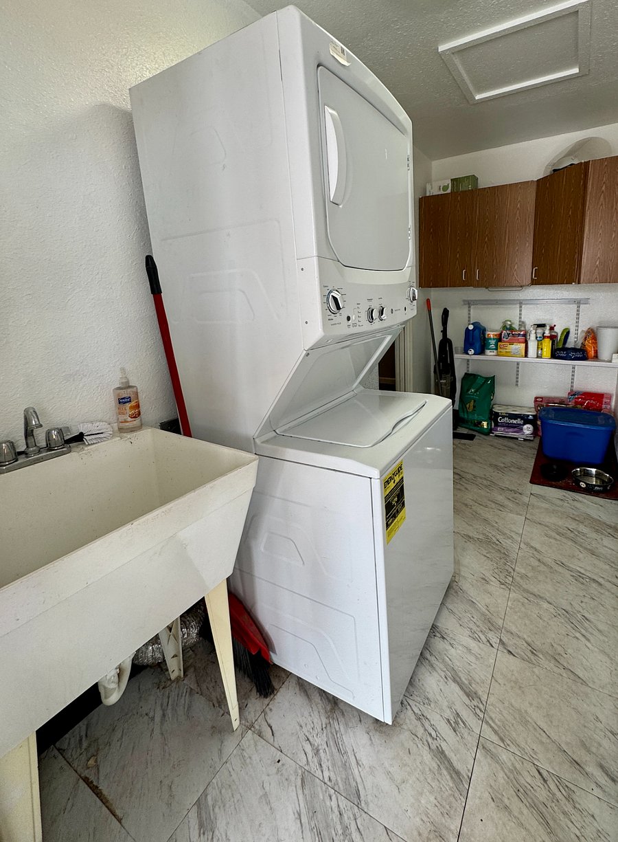 Laundry room has a wash tub and plenty of cabinets for towels and extra bedding
