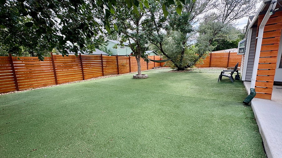 Full turf backyard with a hammock and Adirondack chairs