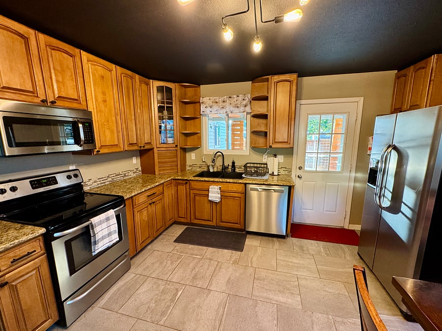 Stainless steel appliances and granite countertops with access to back patio