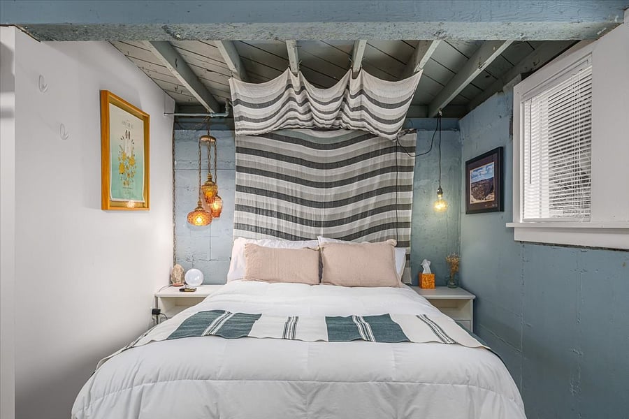 Used as primary bedroom, this downstairs bedroom features sliding barndoor and a closet area, plus windows with garden views (in basement living area) cool all summer!