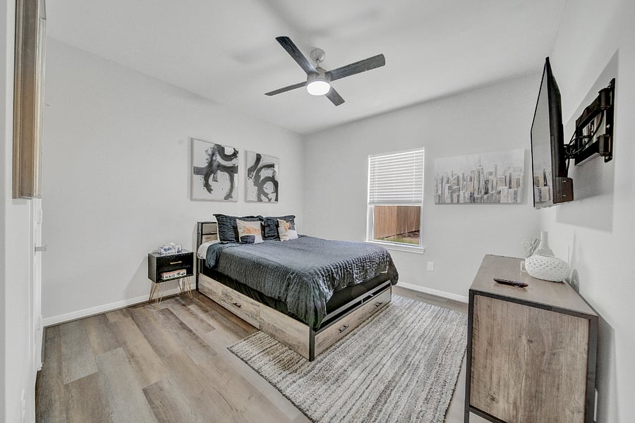 This bedroom with queen bed combines functionality with aesthetic appeal through its use of neutral colors, modern furniture, and minimalistic decor elements, creating an inviting yet uncluttered atmosphere.