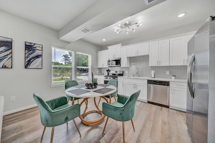 Haywood features a modern kitchen and dining area. The kitchen features white cabinets, soft-close drawers, and brand-new stainless-steel appliances, including a refrigerator and oven.