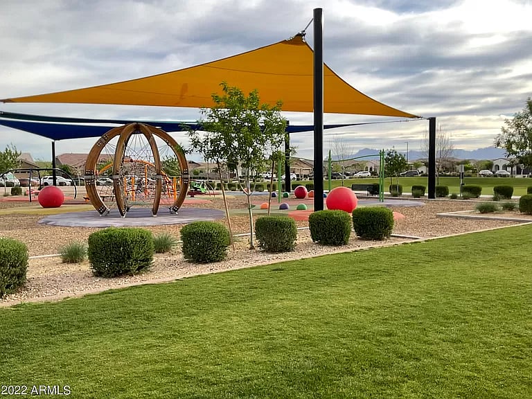 Shaded playground with modern play structures and open grassy areas for families and kids.

