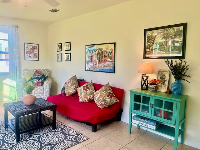 The living room is approx. 300 Sq. Ft, with large windows for a ton of natural light. The space is colorfully decorated with retro posters and floral pillows.