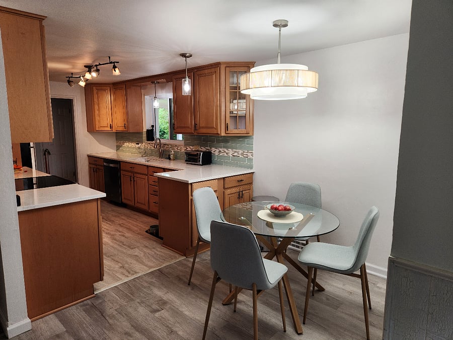 Well-lit kitchen with dishwasher, full sized appliances, dining table