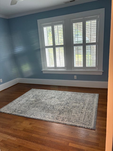 This is the "Sitting Room/Office" space - it is sunny with an area rug. The roll top desk is in this room, along with white shelves, a television, and a small loveseat/futon and chair.