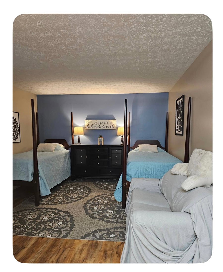 Large primary bedroom with ensuite bath- comfortably fits a king bed and seating area. Currently shown with two beds; can be configured with queen or cleared for your own furnishings.