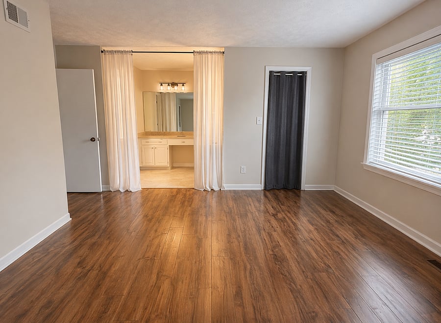 Empty primary bedroom highlighting its expansive layout, natural lighting and access to ensuite bath.