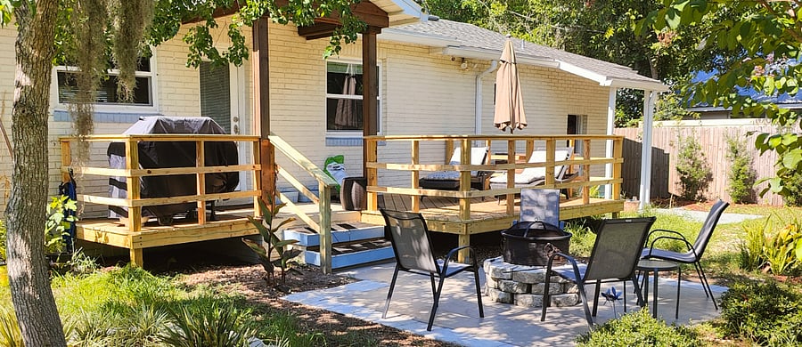 Back deck with BBQ grill, two sun loungers, parasol, fire pit and four chairs.