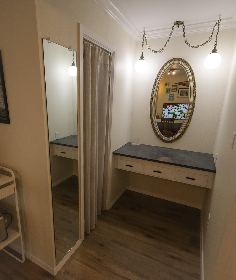 Vanity and full-length mirror inbetween the entrance to the walk-in closet.