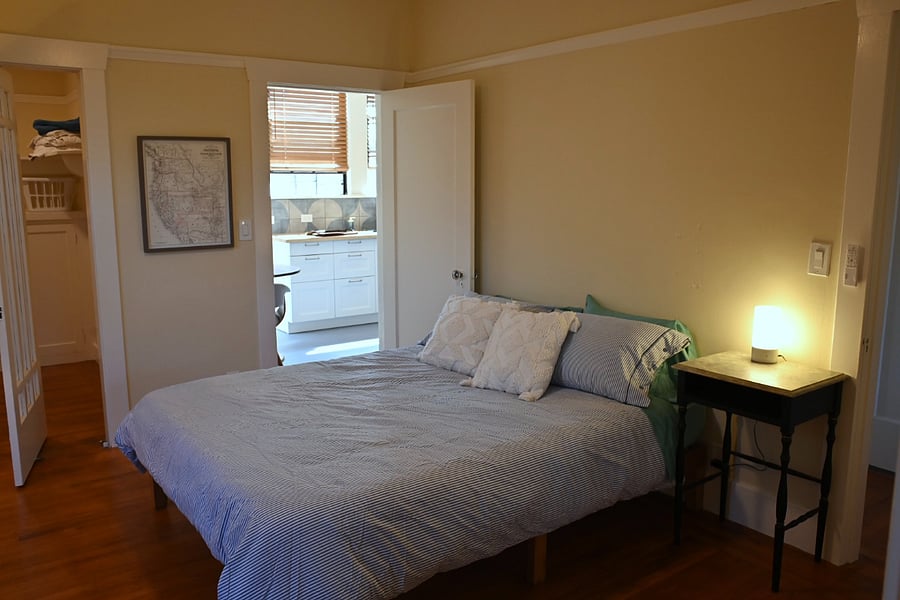 bedroom, kitchen in background