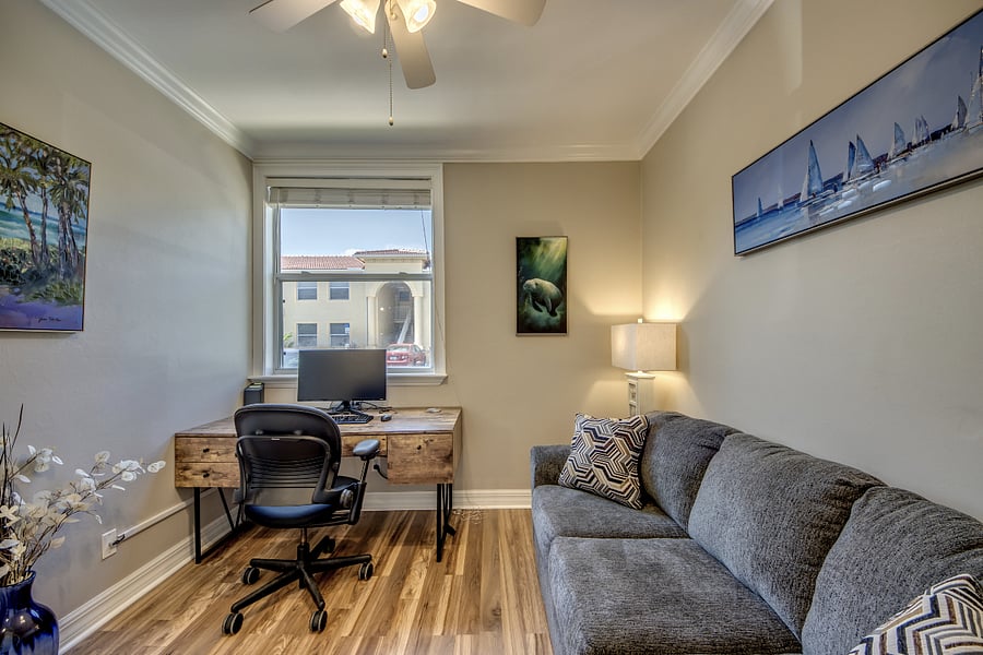 Third bedroom with desk workspace, extra monitor, and couch.