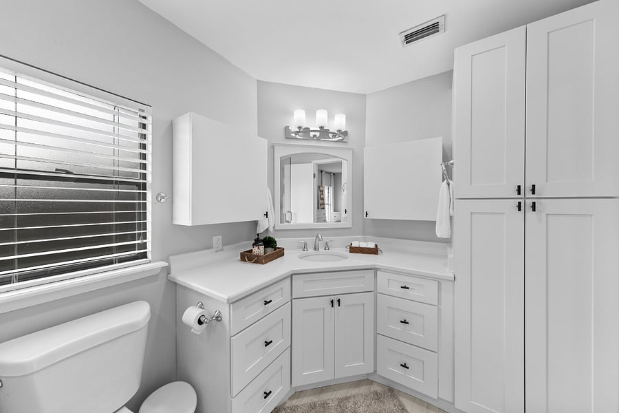 Renovated bathroom with glass shower enclosure and quartz countertops. .